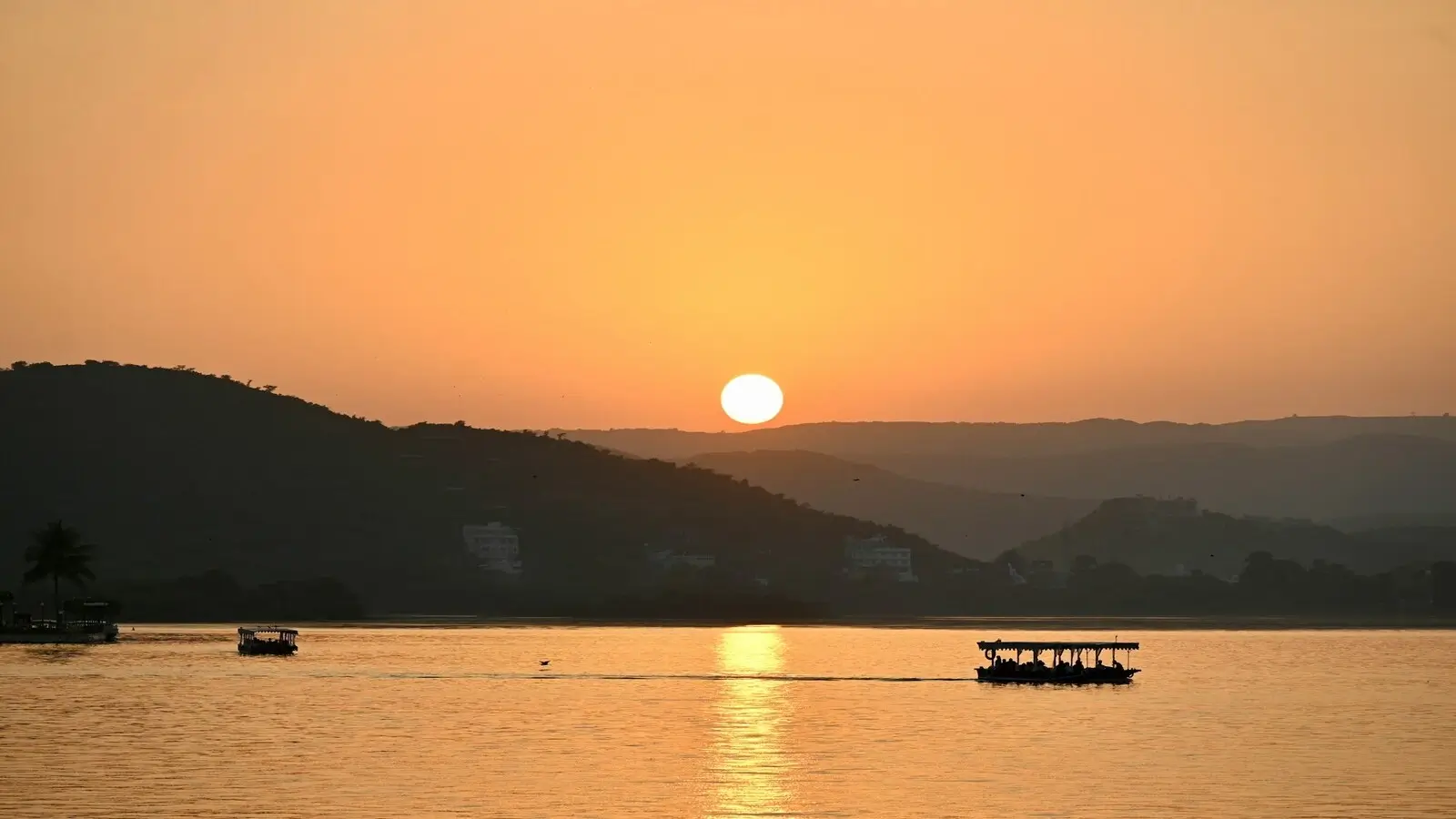 Golden sunset reflecting on Lake Pichola with City Palace in the background in Udaipur