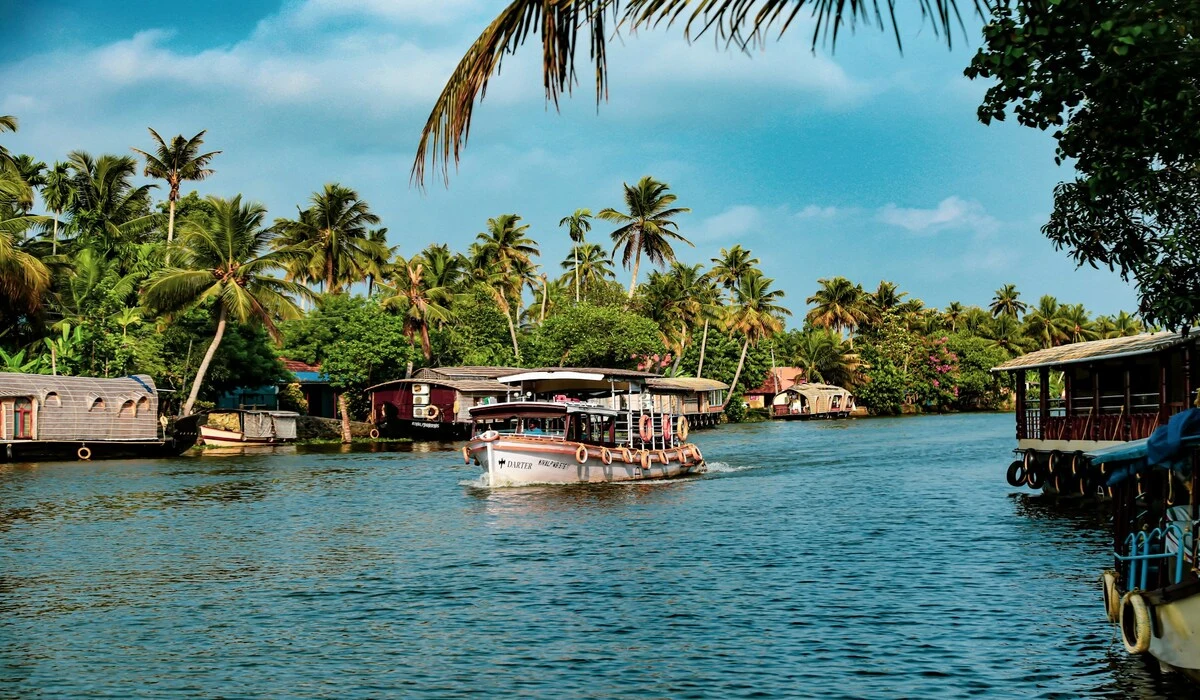 Houseboat cruising through Kerala backwaters surrounded by palm trees in dry February season